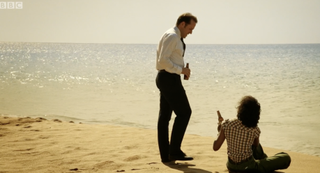 Richard and Camille share a drink on the beach in Death in Paradise season 1 episode 8
