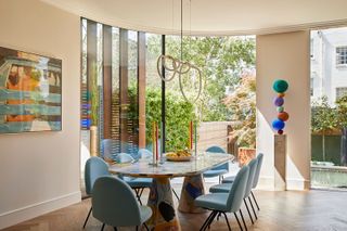 a dining room with a curved patio door, colorful artwork and furniture, and a view out to the garden