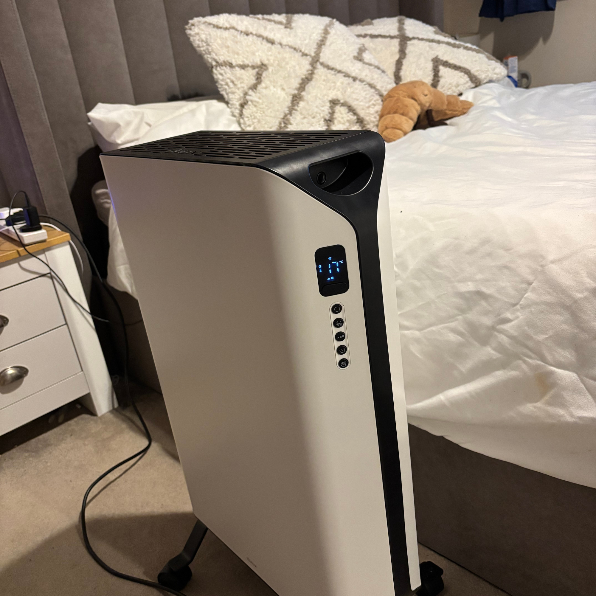 Duux Edge Oil 2000W Oil-Filled Radiator positioned on carpeted floor, by the side of a bed
