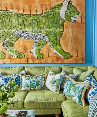 colorful TV room with blue walls, green tiger batik, green sofa and green and blue patterned cushions