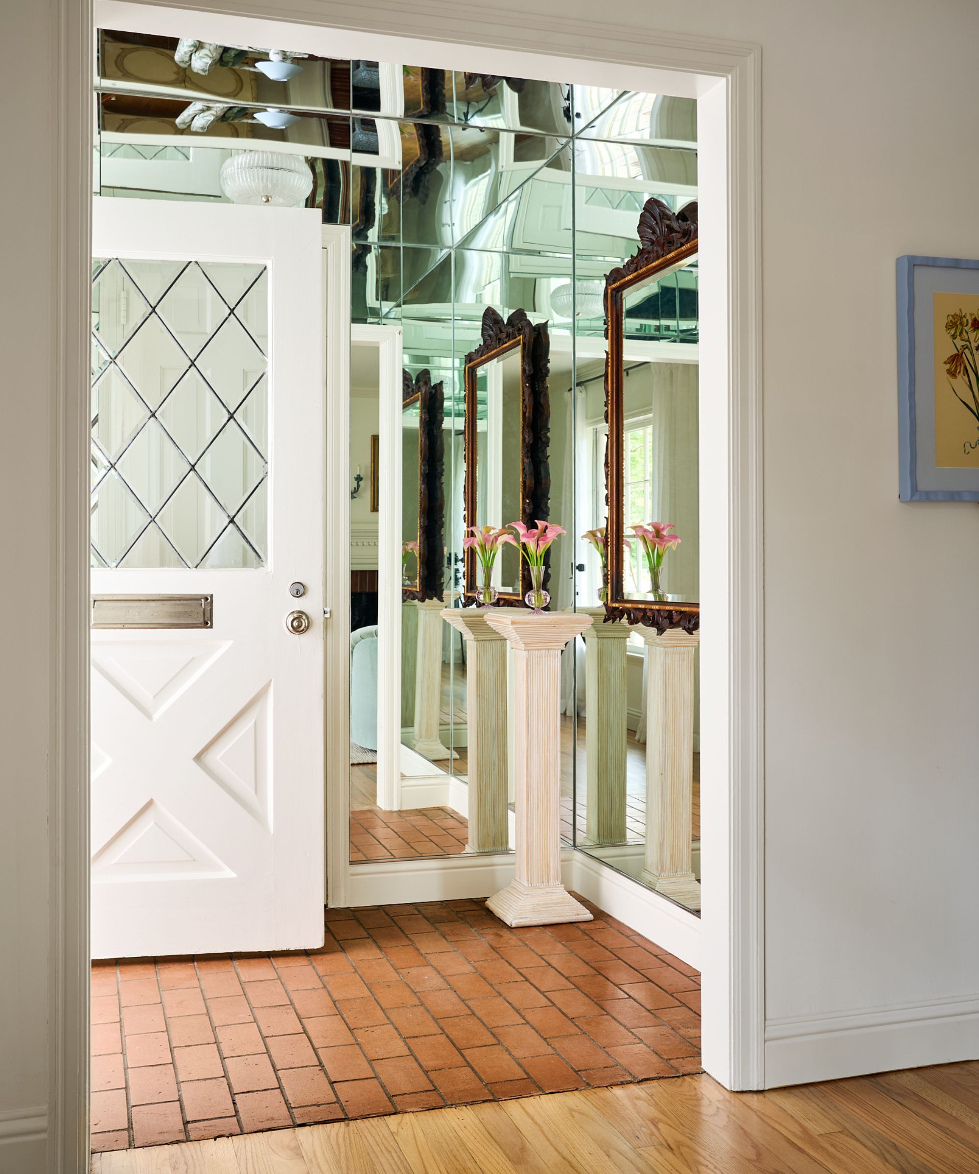 a neutral entry with brick tiles and mirror tiled walls and ceiling