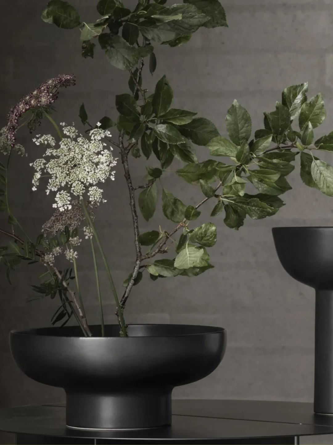 A black shallow ikebana vase with stems