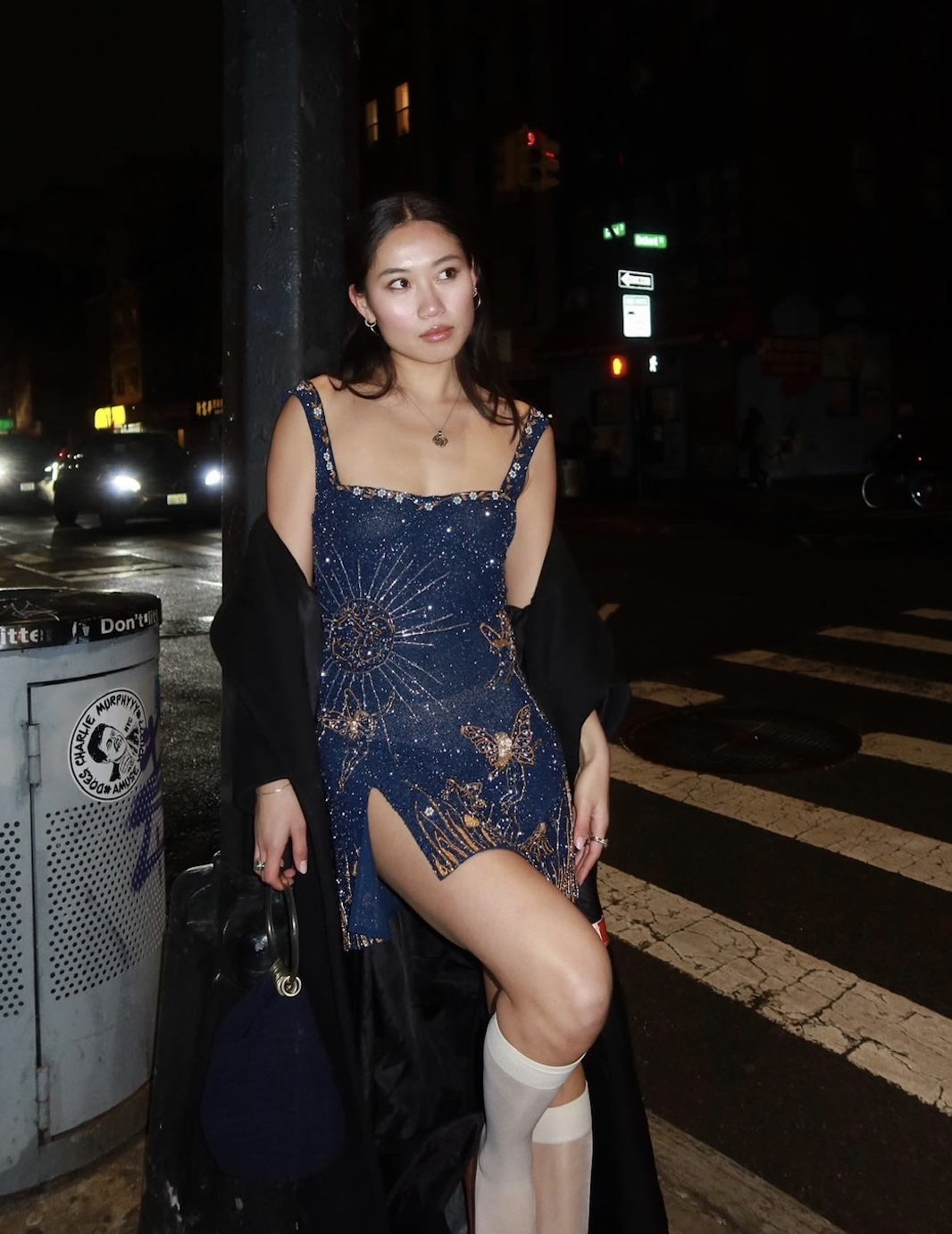Vivian Li wearing a blue beaded dress, black coat, white socks, and blue bag