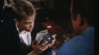 Chad Allen stares intently at a snow globe in his hands while sitting on the floor in. the St Elsewhere series finale.