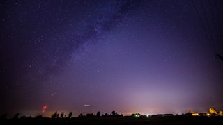 Draconid meteors streak across the night sky. The Milky Way can also be seen stretching across the star-studded sky. 