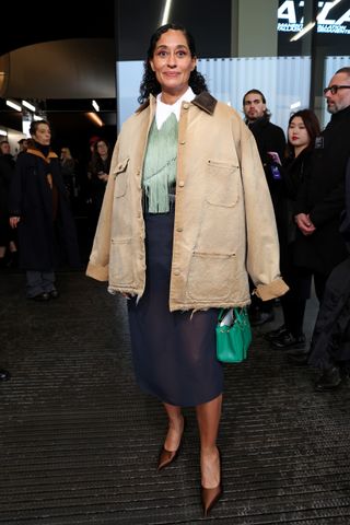 Tracee Ellis Ross wearing a utility style coat, a fringe top, and a semi-sheer midi skirt