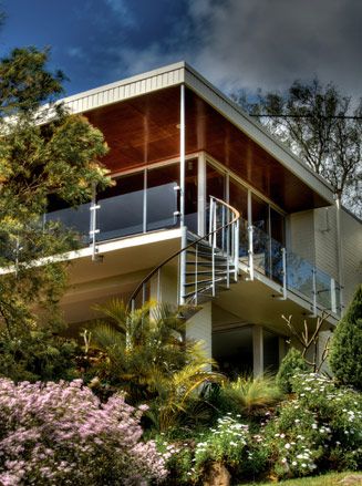 A large white mansion with a glass front and exterior wall. 