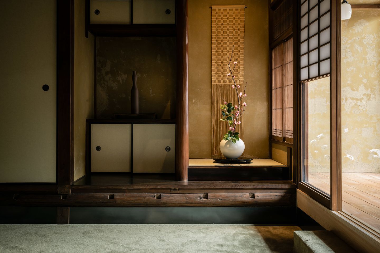 The warm, welcoming interiors of a traditional Japanese inn, with layered textiles, wood marquetry, and paper lanterns.