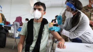 A health care worker immunizes Juan Guevara with the Pfizer COVID-19 vaccine at the Miami Dade College North Campus on March 10, 2021, in North Miami, Florida. At the beginning of August, Florida was reporting an average of 21,706 new cases of COVID-19 every day, The New York Times reported.