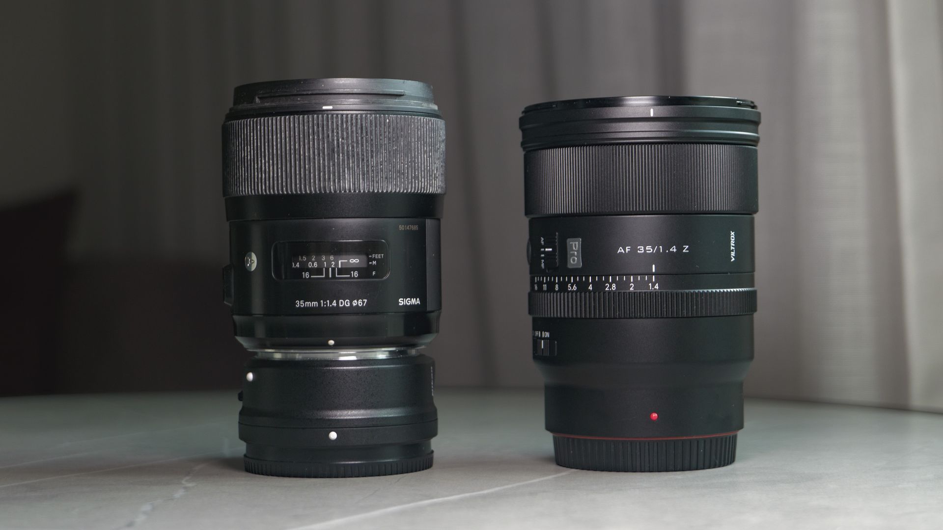 Viltrox AF 35mm F1.4 Pro lens alongside the Sigma 35mm f1/.4 DG Art lens with Nikon F to Z-mount adapter, on a white marble table