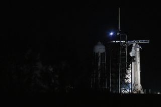 a white rocket on a launch pad with smoke billowing up from beneath it