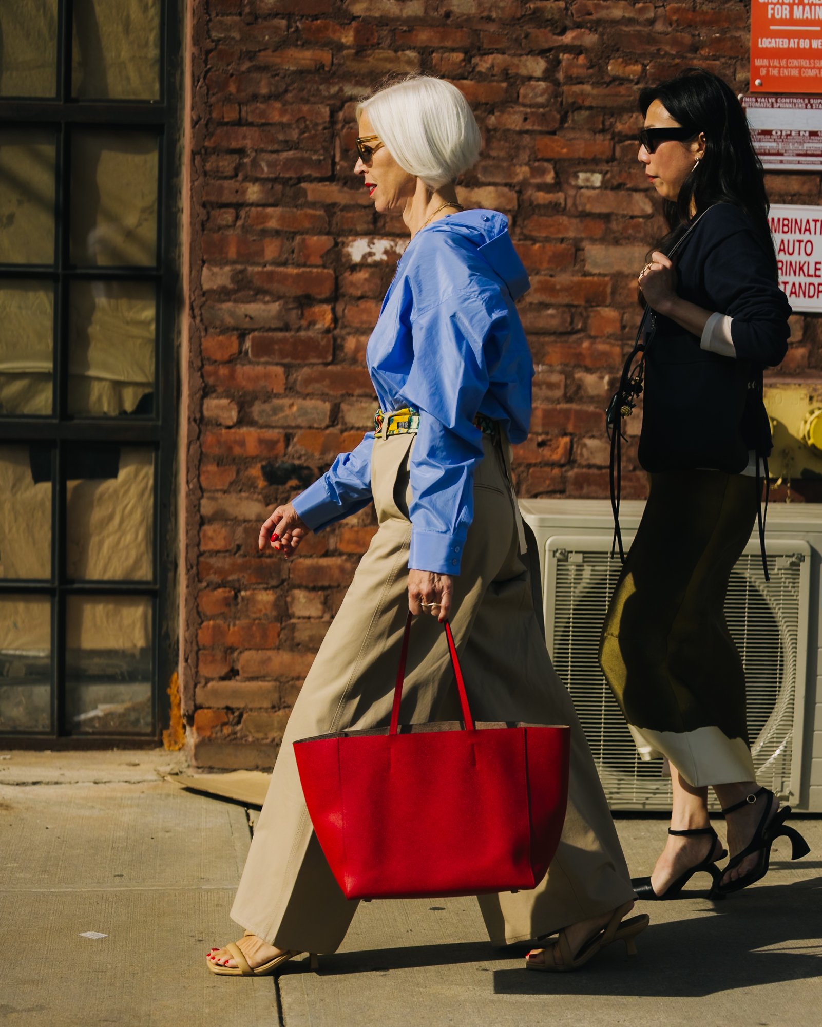 a woman at new york fashion week carrying a red leather tote bag