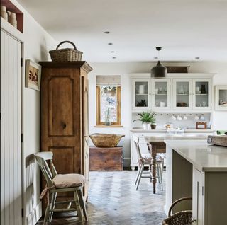 white kitchen with antique wooden dresser and warm parquet wood flooring