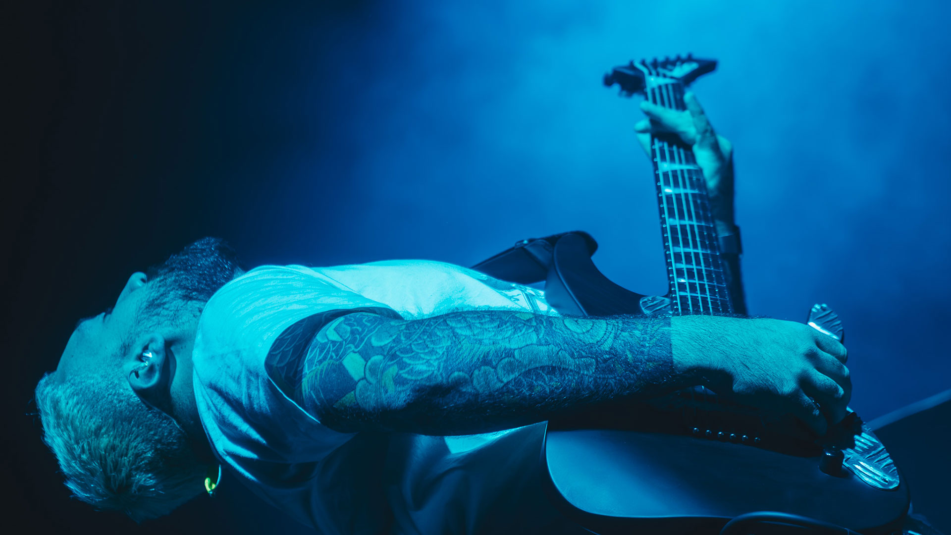 Erhan Alman bending over backwards while playing his Jackson electric guitar