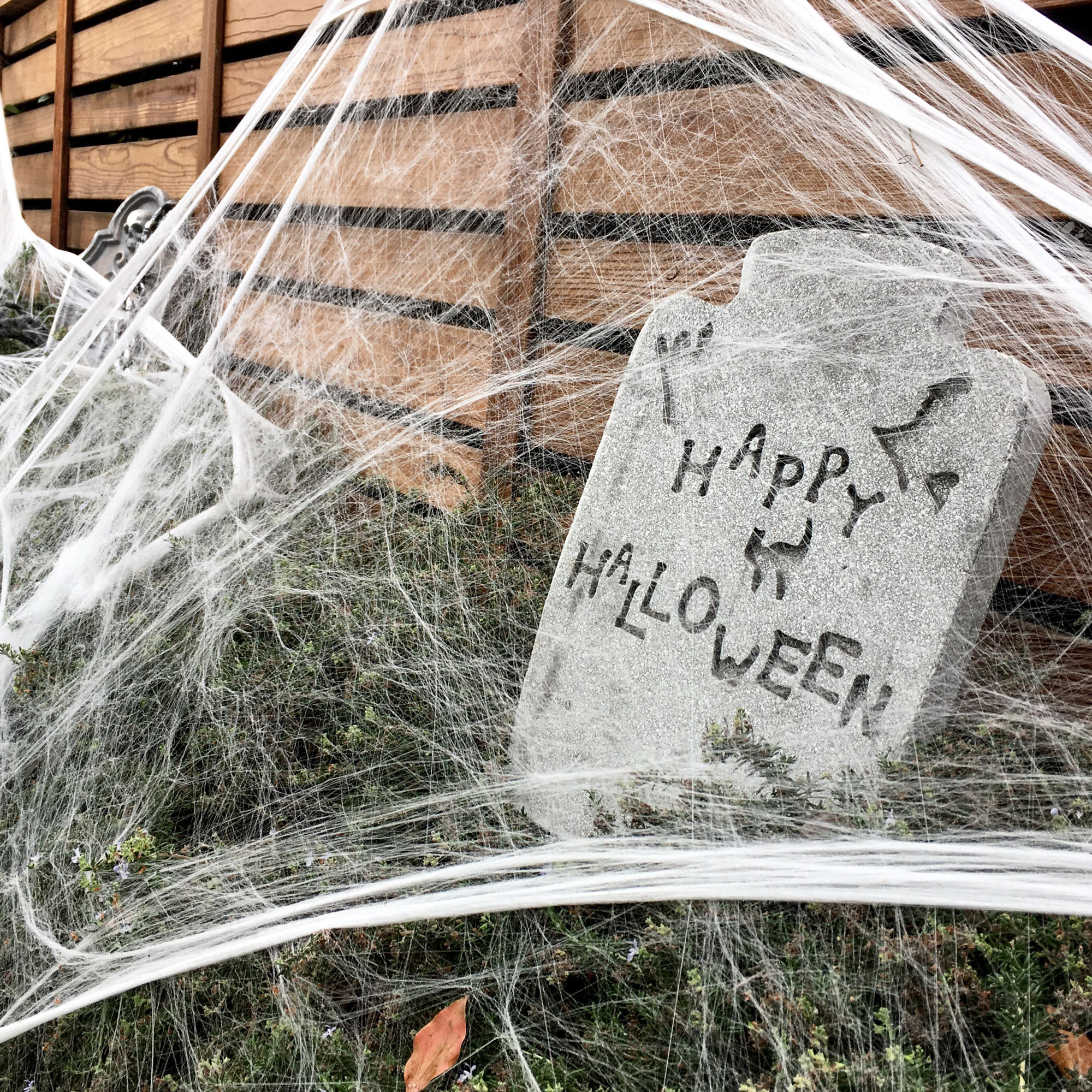Grey halloween tombstone covered in faux cobwebs