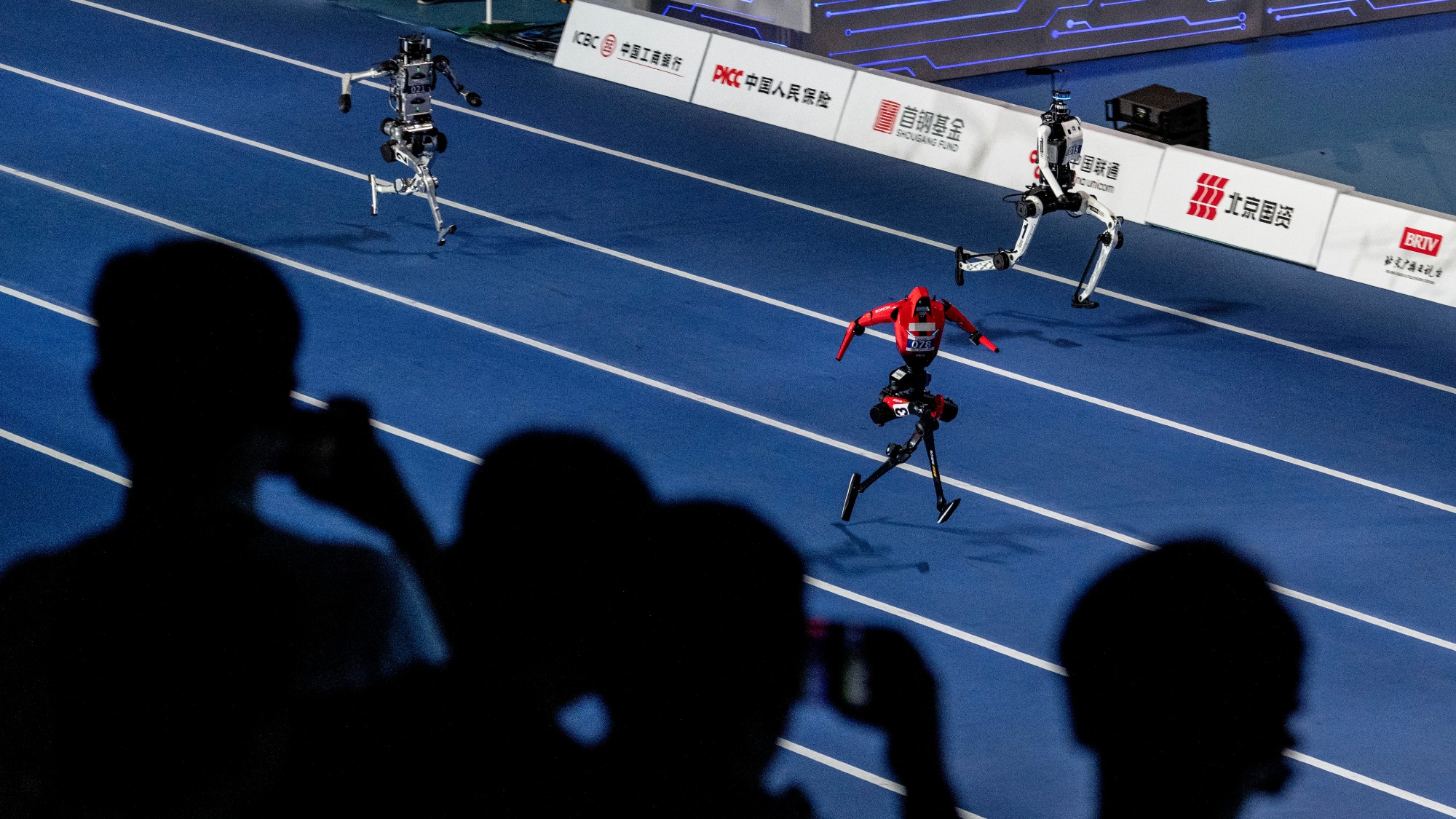 Spectators watching sprinting humanoid robots during the opening ceremony of the 2nd World Robot Games in Beijing