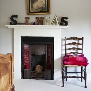 bedroom fireplace with red chair and decorated mantel