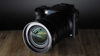 Hasselblad XCD 35-100E lens on a wooden surface in a moodily lit environment