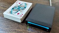 Photograph of the world's smallest Nintendo Wii, "Short Stack", alongside a deck of playing cards for scale.