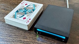 Photograph of the world's smallest Nintendo Wii, "Short Stack", alongside a deck of playing cards for scale.