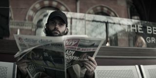 Joe Goldberg sat on a bench reading a newspaper in You season 4