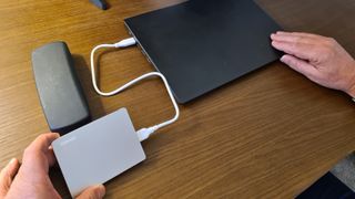 Toshiba Canvio Flex external hard drive in use on wooden desk, connected to laptop via USB cable