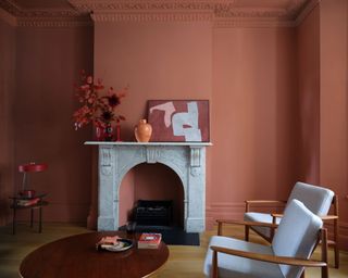 Terracotta walls in traditional living room with grey fireplace, autumn leaves and eye-catching artwork