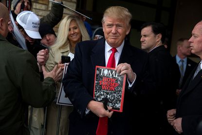 Republican presidential candidate Donald Trump holds a copy of Time Magazine in Iowa