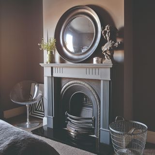 A bedroom with a fireplace and a round mirror atop