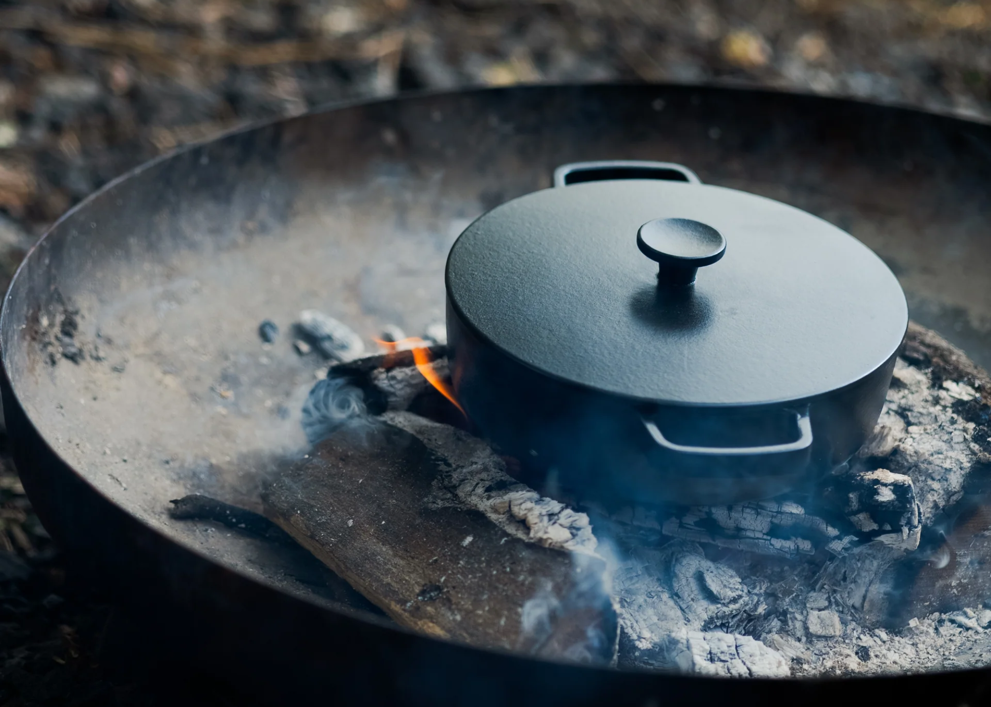 A black cast iron pot on a cooker with charcoal