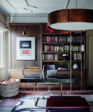 study with wooden bookcase, modern desk and copper ceiling light