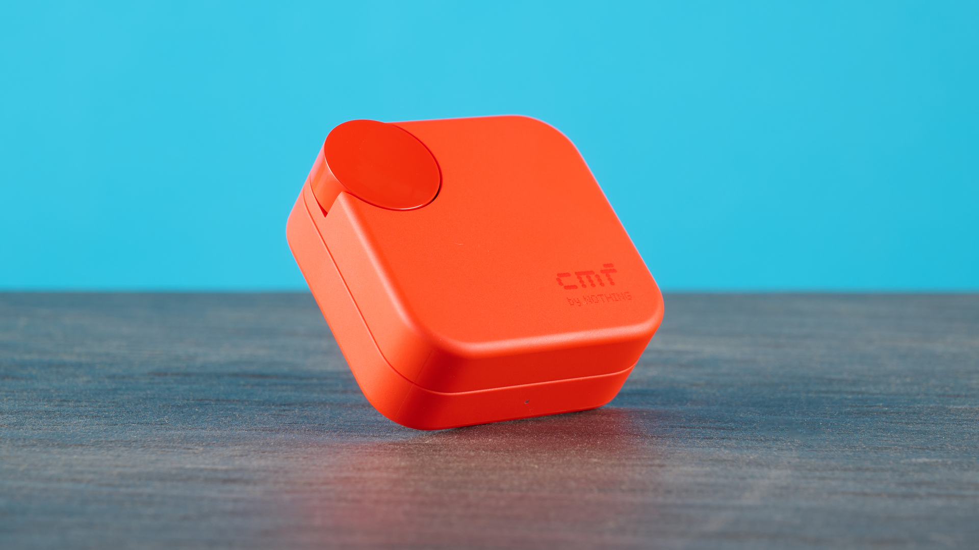 cmf buds 2a in the orange colorway photographed in front of a blue background