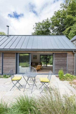 grey patio outside timber building with small steel furniture