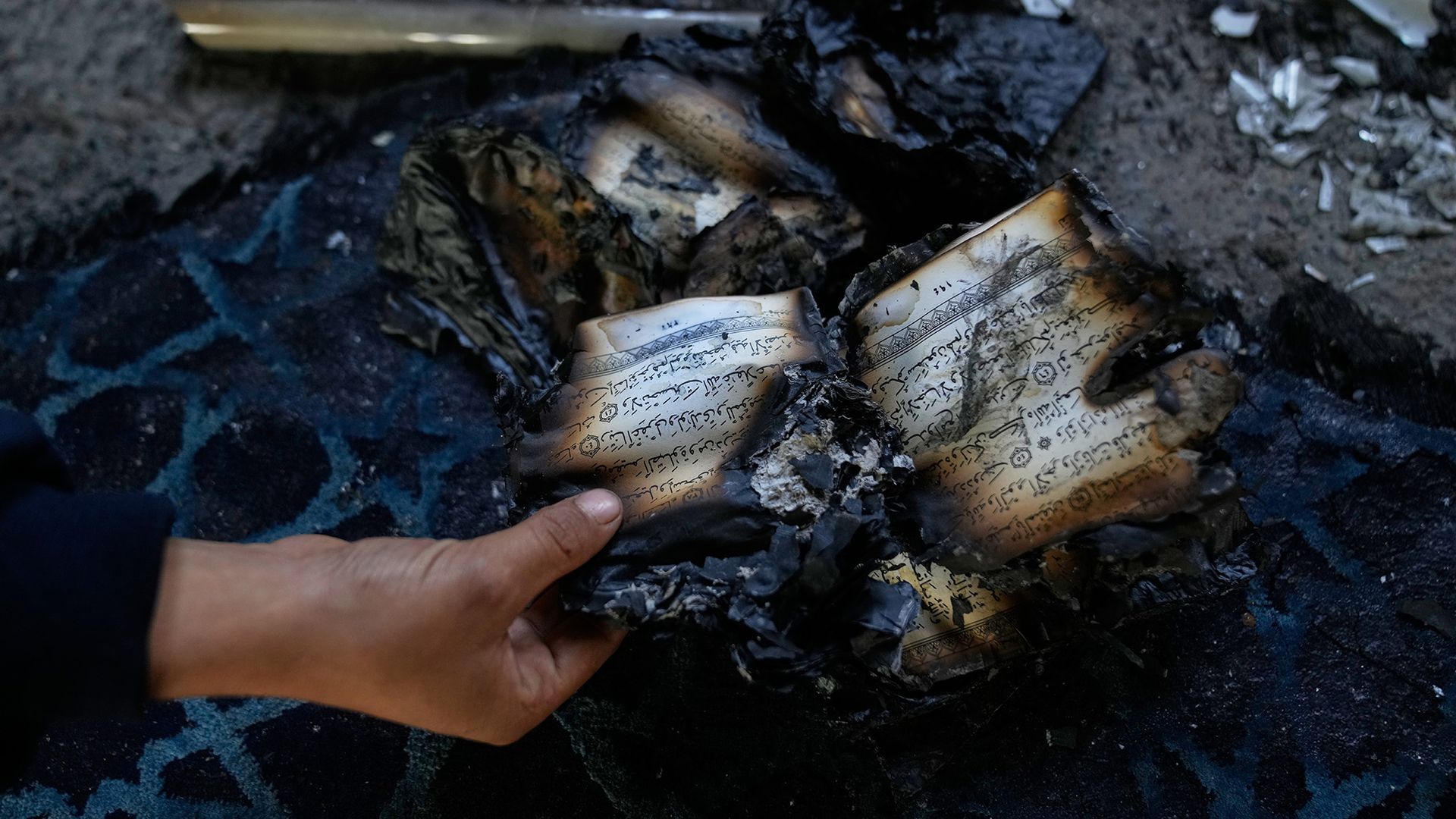 
                                A boy inspects burnt copies of the Quran inside a mosque that was torched and defaced by Israeli settlers in the West Bank
                            