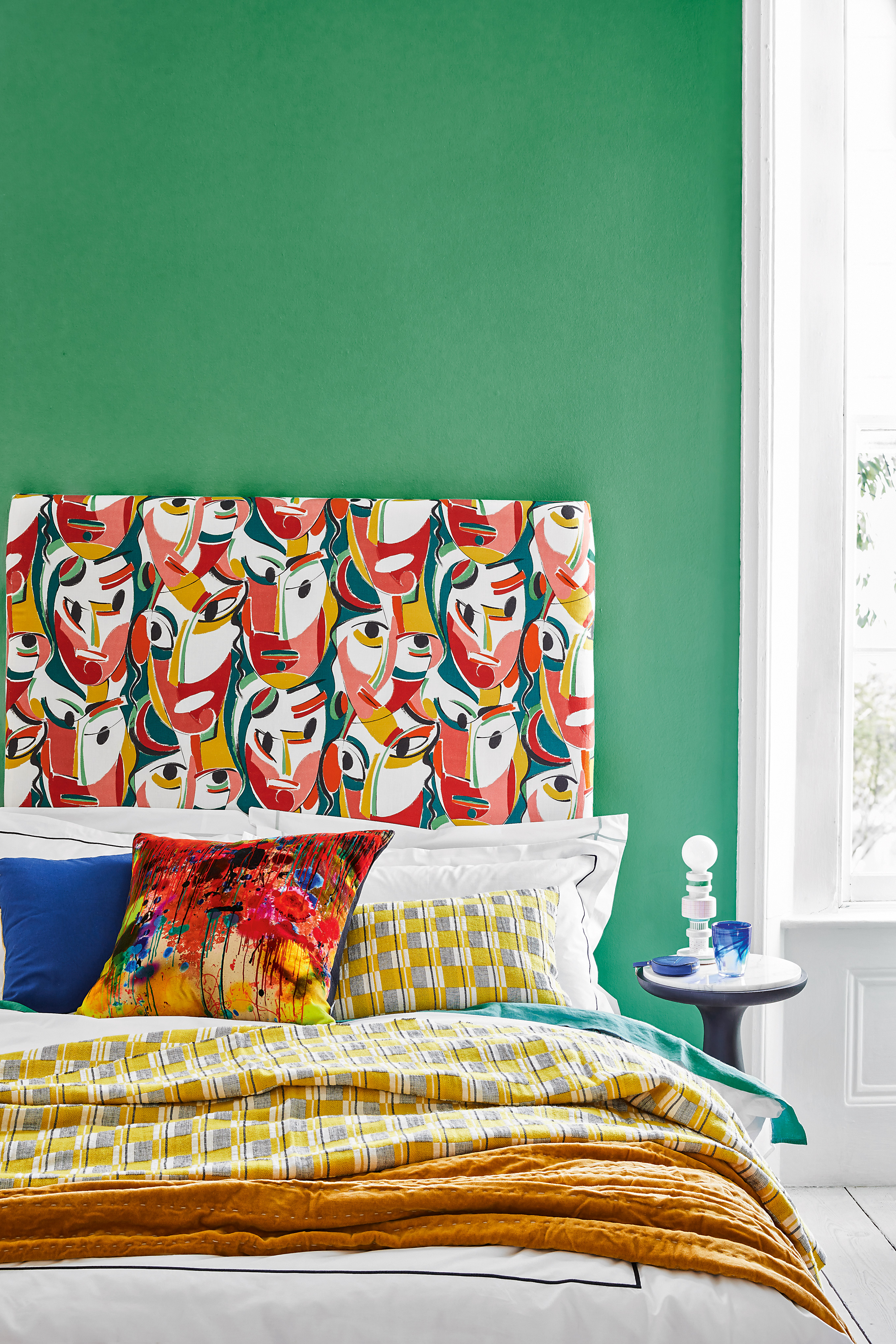 Green bedroom with bold patterned headboard