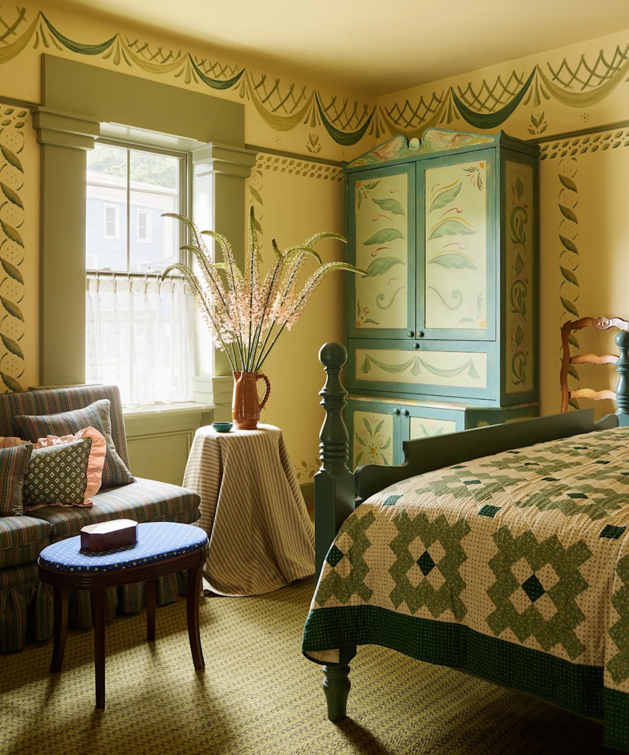 folk hotel bedroom at the six bells with handpainted green decor and a bed styled with a patchwork quilt