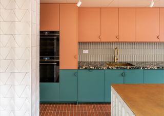 A colorful kitchen with blue lower cabinets and orange/peach upper cabinets