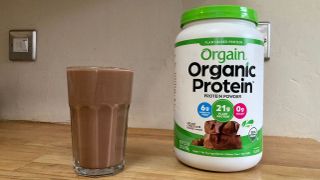Orgain Organic Protein Powder mixed shake in a glass and tub