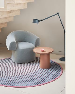 A blue armchair with a side table over a circular purple rug