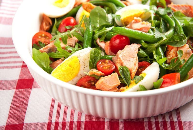 A salad of raw vegetables with eggs and salmon.