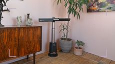 Shark TurboBlade fan in the corner of a pink room with houseplant and a wooden sideboard