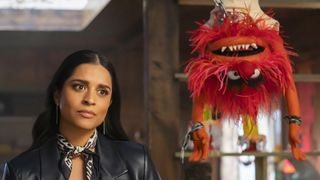 Nora Singh stares at someone off-camera as Animal hangs upside down next to her in The Muppets Mayhem