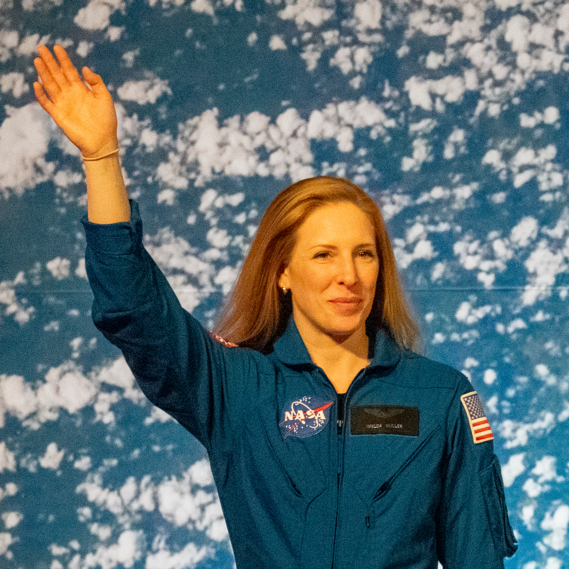 people in blue jumpsuits smile and wave.
