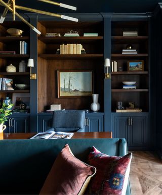 navy dark blue home office with dark wooden shelving and desk and styled bookshelves