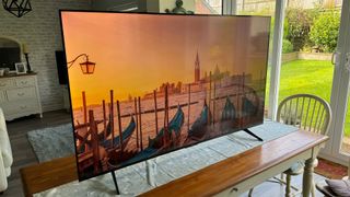 TCL P755K 65-inch 4K TV on wooden table in front of glass doors with Venice on screen