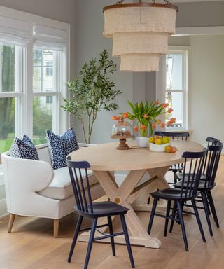 A modern farmhouse-style dining area with pale grey leather banquette, navy chairs and oak oval table
