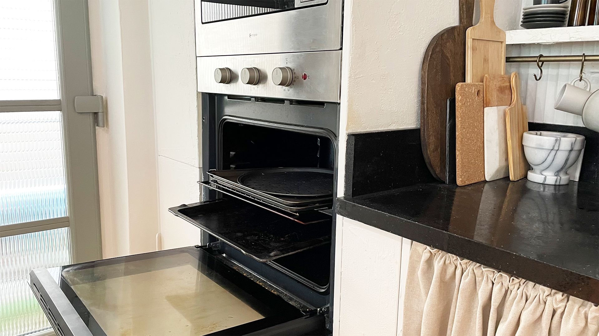 open oven with trays and racks pulled out ready to be removed to show how to clean an oven with baking soda
