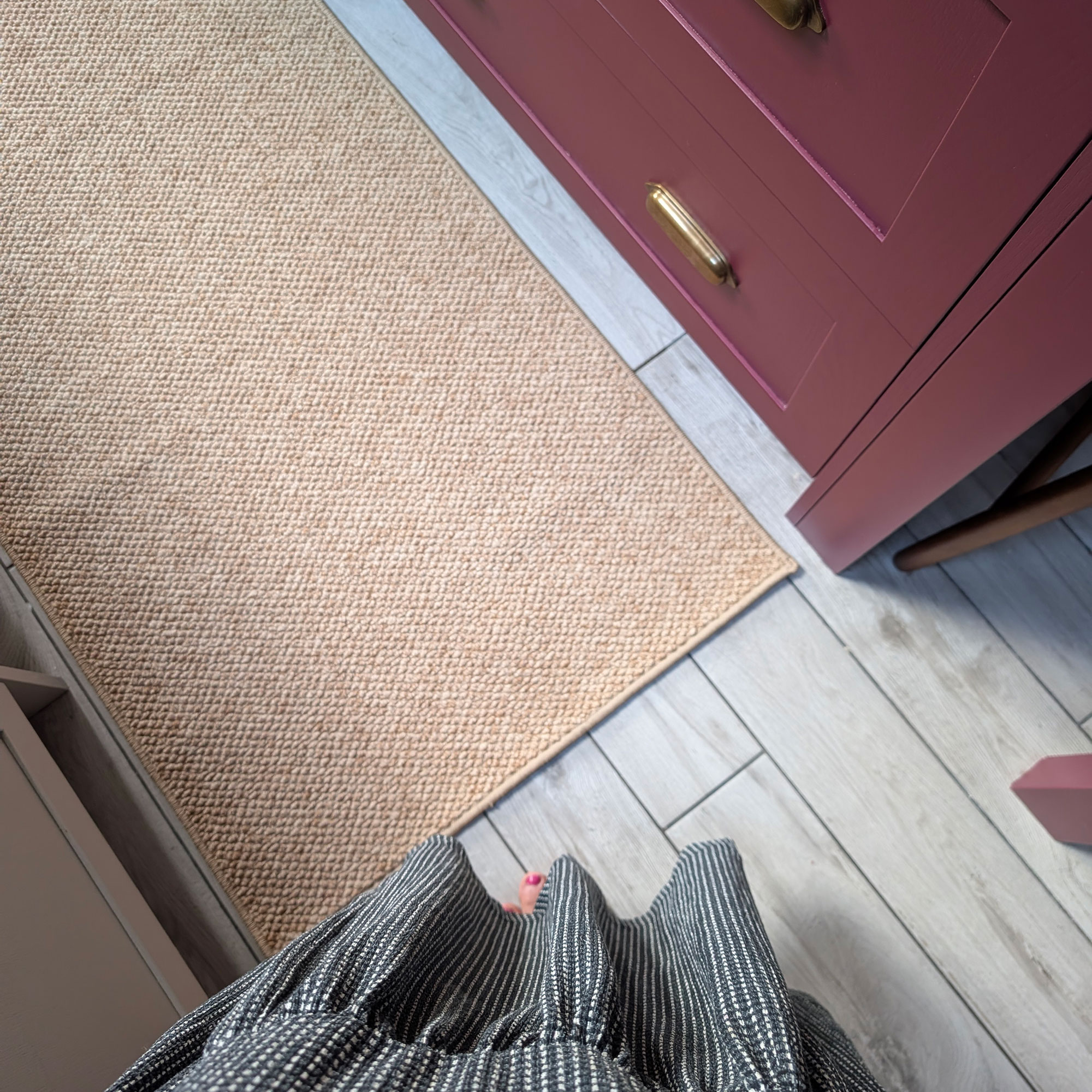 Point of view of person looking down onto grey kitchen floor with sisal style runner