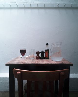 Table laid for one at Fergus Henderson's restaurant featuring a jug of water, salt and pepper pot (wood colour), glass and red wine glass.