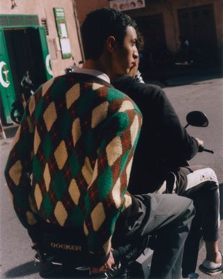 Man sat on motorbike wearing colourful jumper